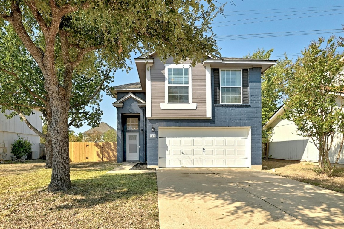 a front view of a house with a yard garage and a tree