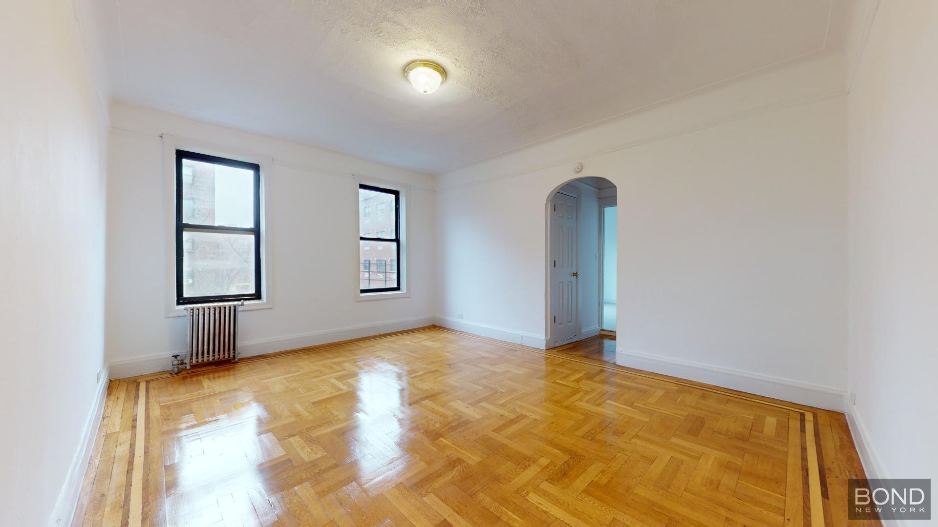 a view of an empty room with window and wooden floor