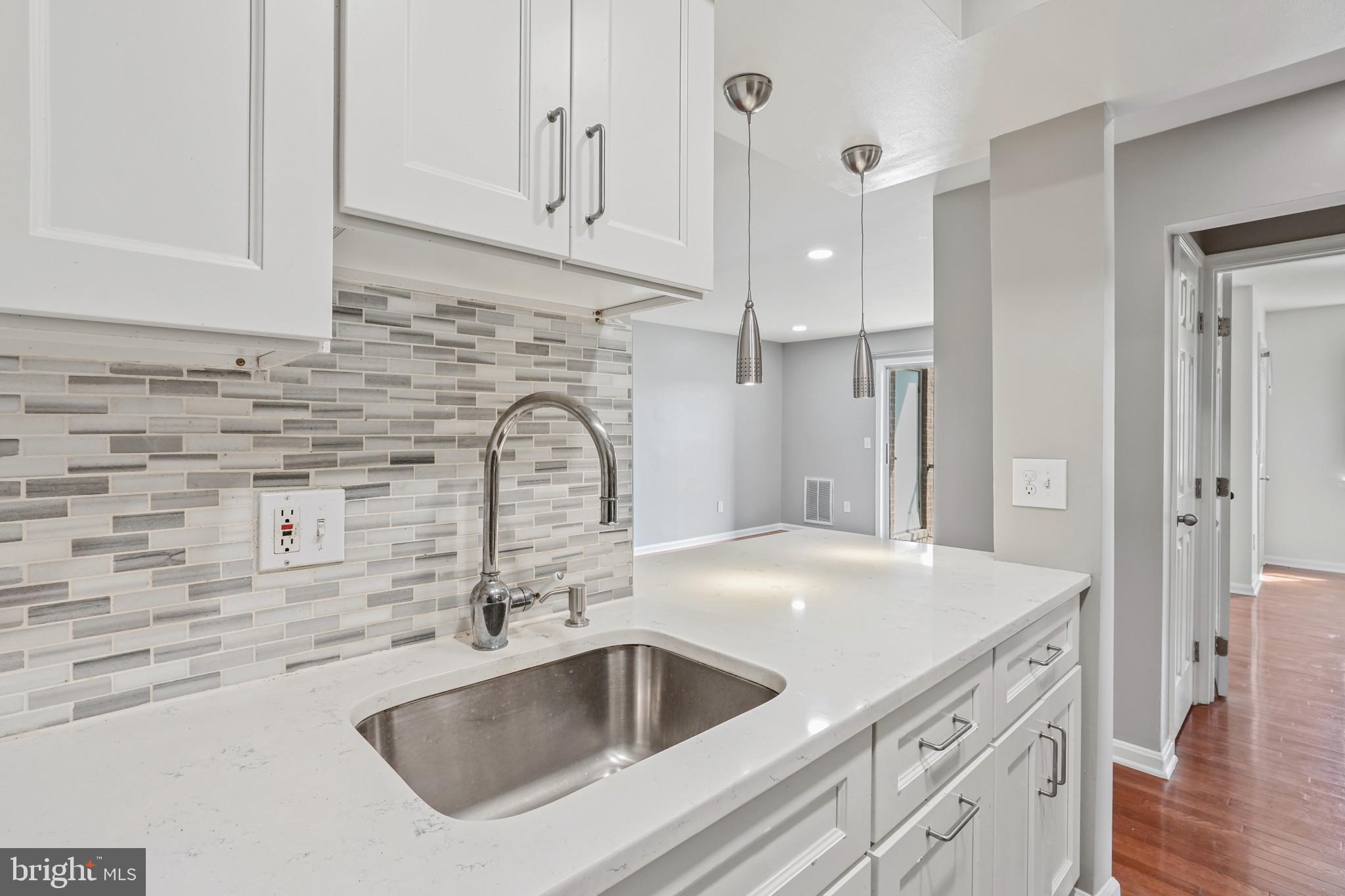 a view with granite countertop a sink and a wooden floor