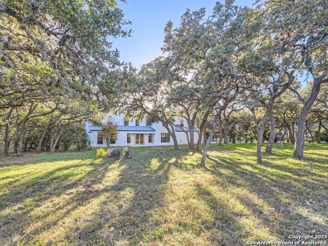 a view of a house with a big yard and large trees