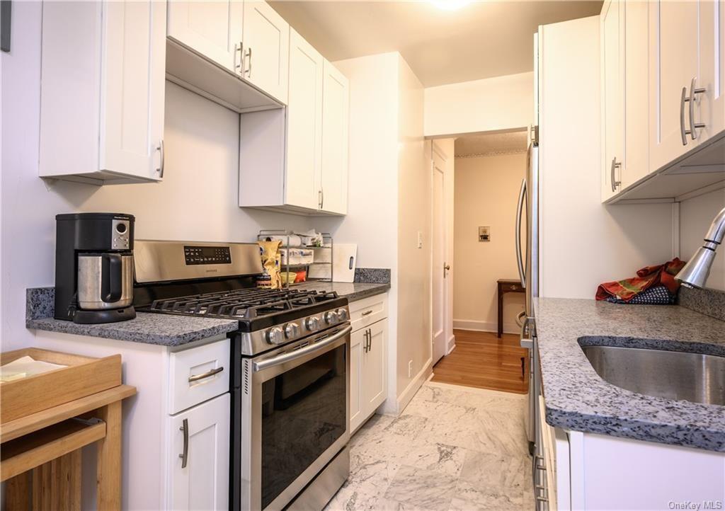 Kitchen featuring stainless steel gas stove, light hardwood / wood-style flooring, sink, and white cabinets