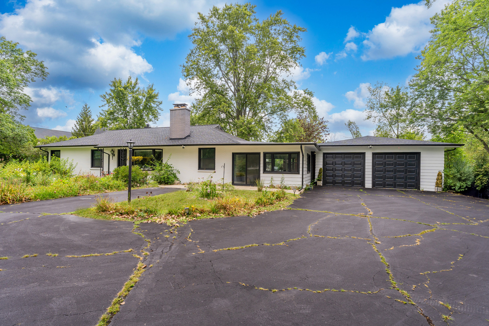 a front view of a house with a garden and trees