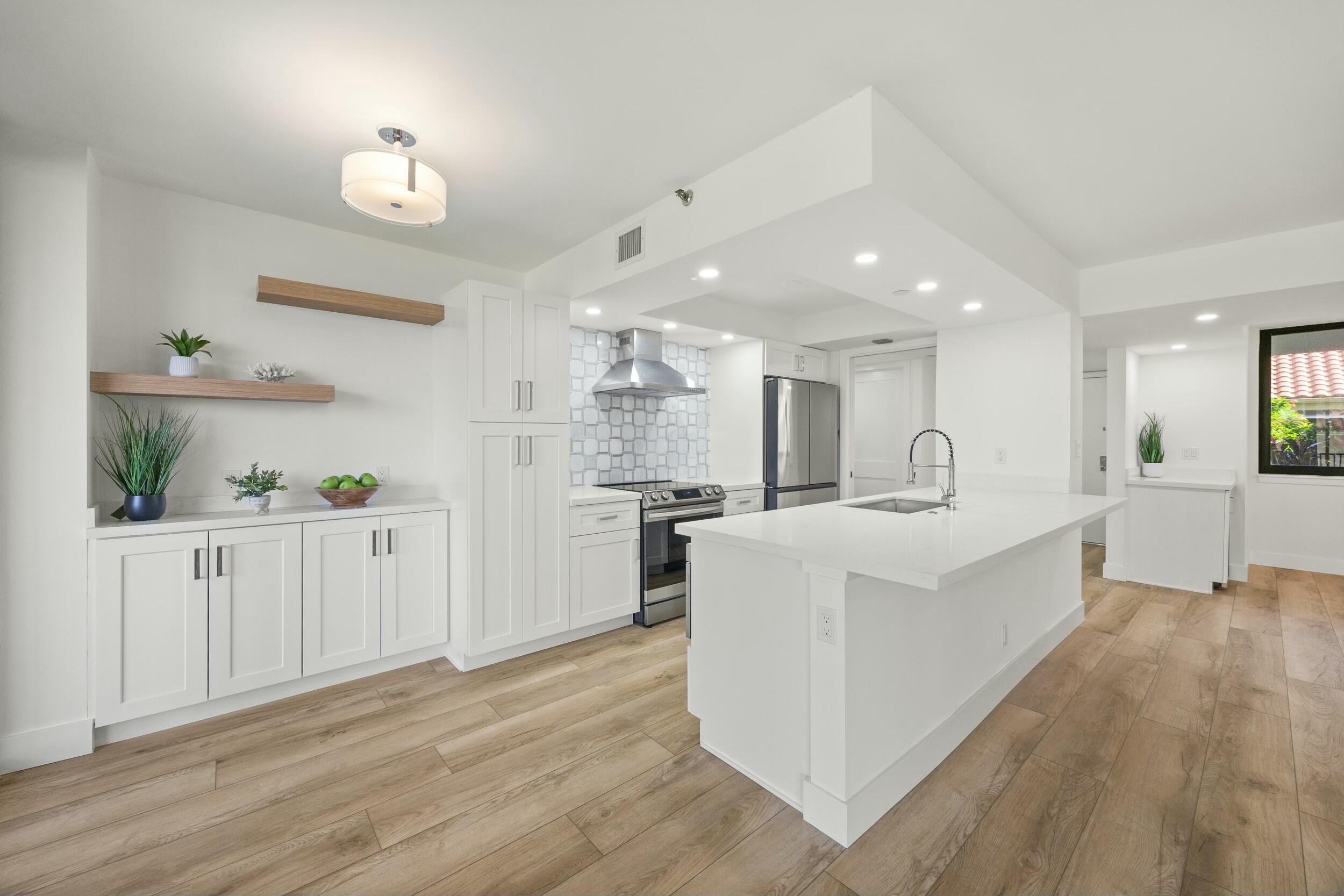 a large white kitchen with kitchen island a sink a center island stainless steel appliances and a cabinets