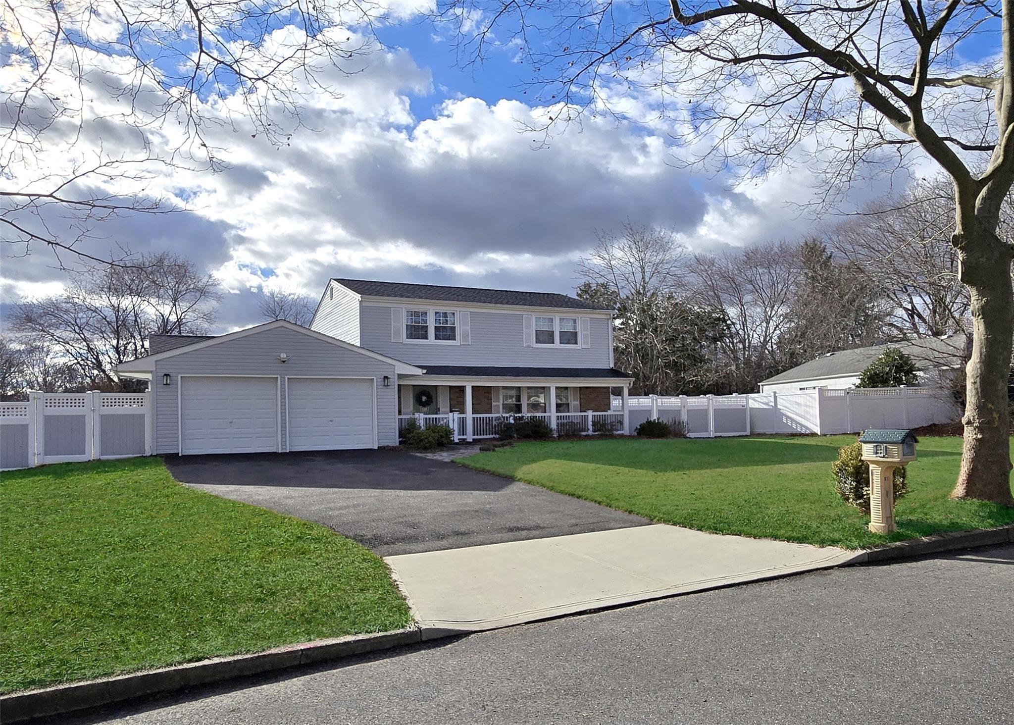 View of front of house featuring a front yard, a porch, and a garage