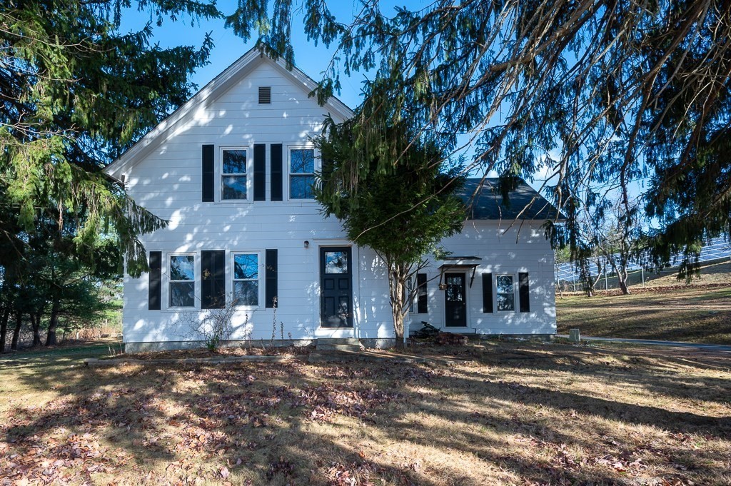 a front view of a house with a tree in front