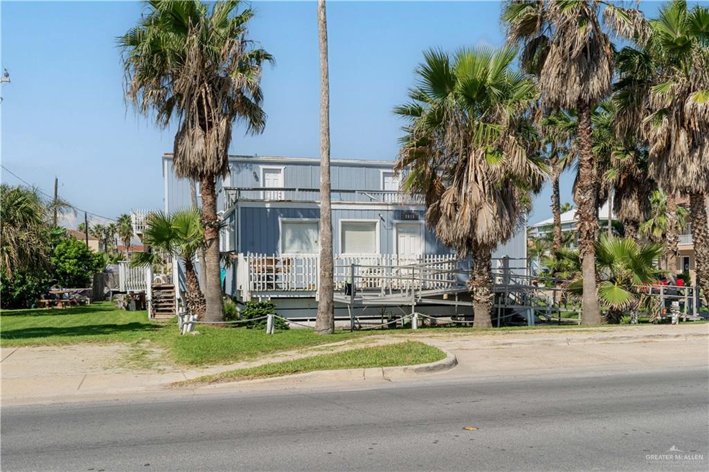 a view of a house with a yard and palm trees