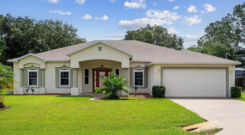 Front view: Portico-Covered entrance way with 2 columns and travertine flooring, decorative door with 2 sidelights