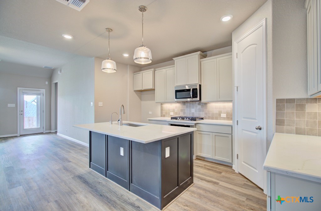 a kitchen with a sink a stove a refrigerator and white cabinets