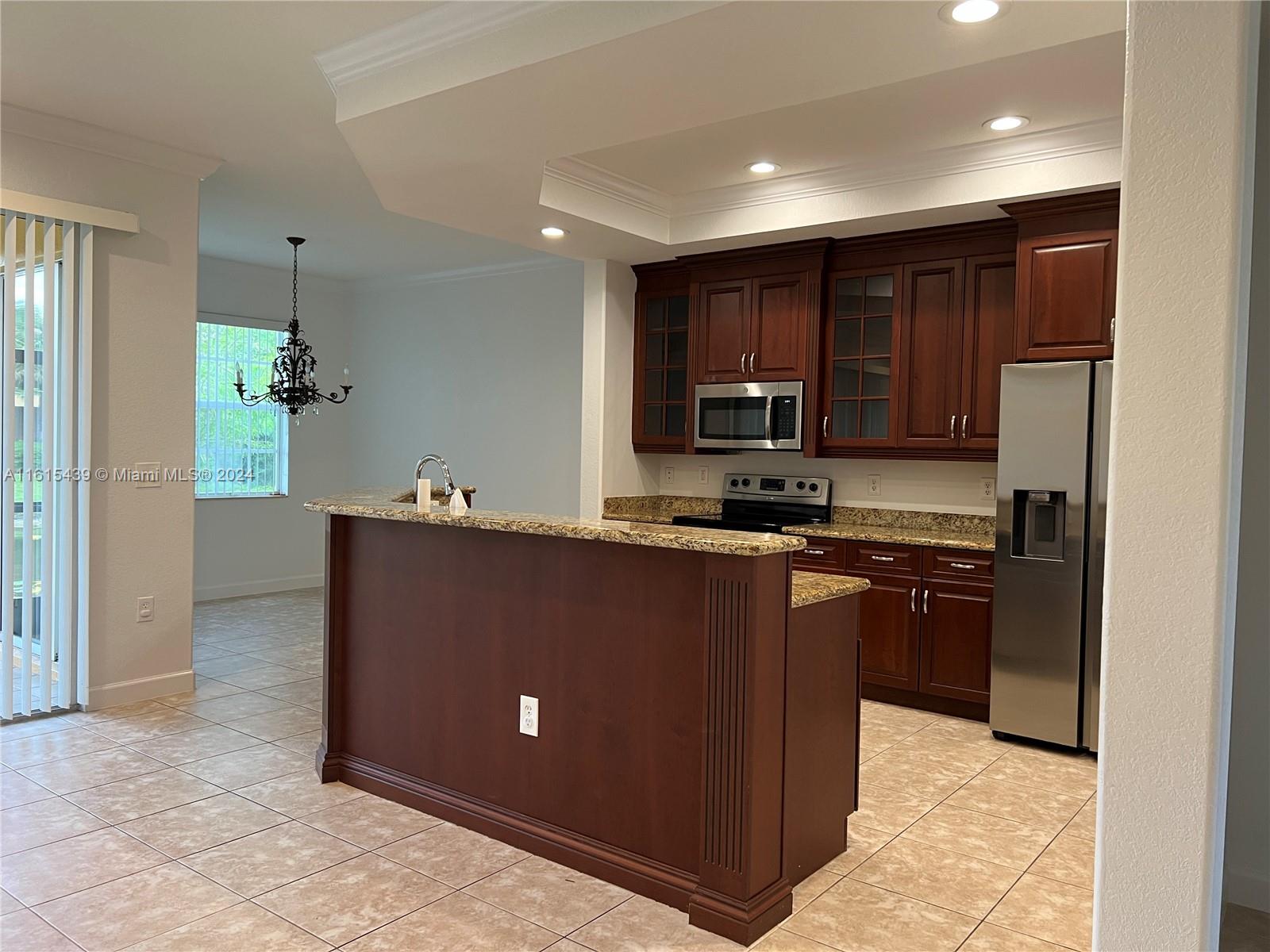 a kitchen with kitchen island granite countertop stainless steel appliances cabinets a sink and a counter top space