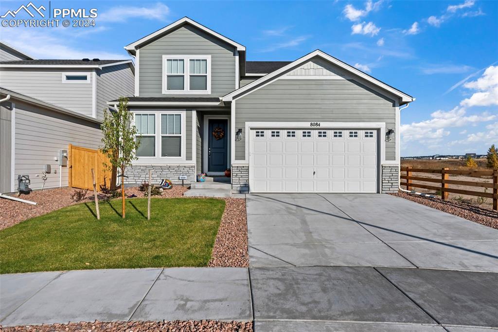 View of front of home with a front yard and a garage