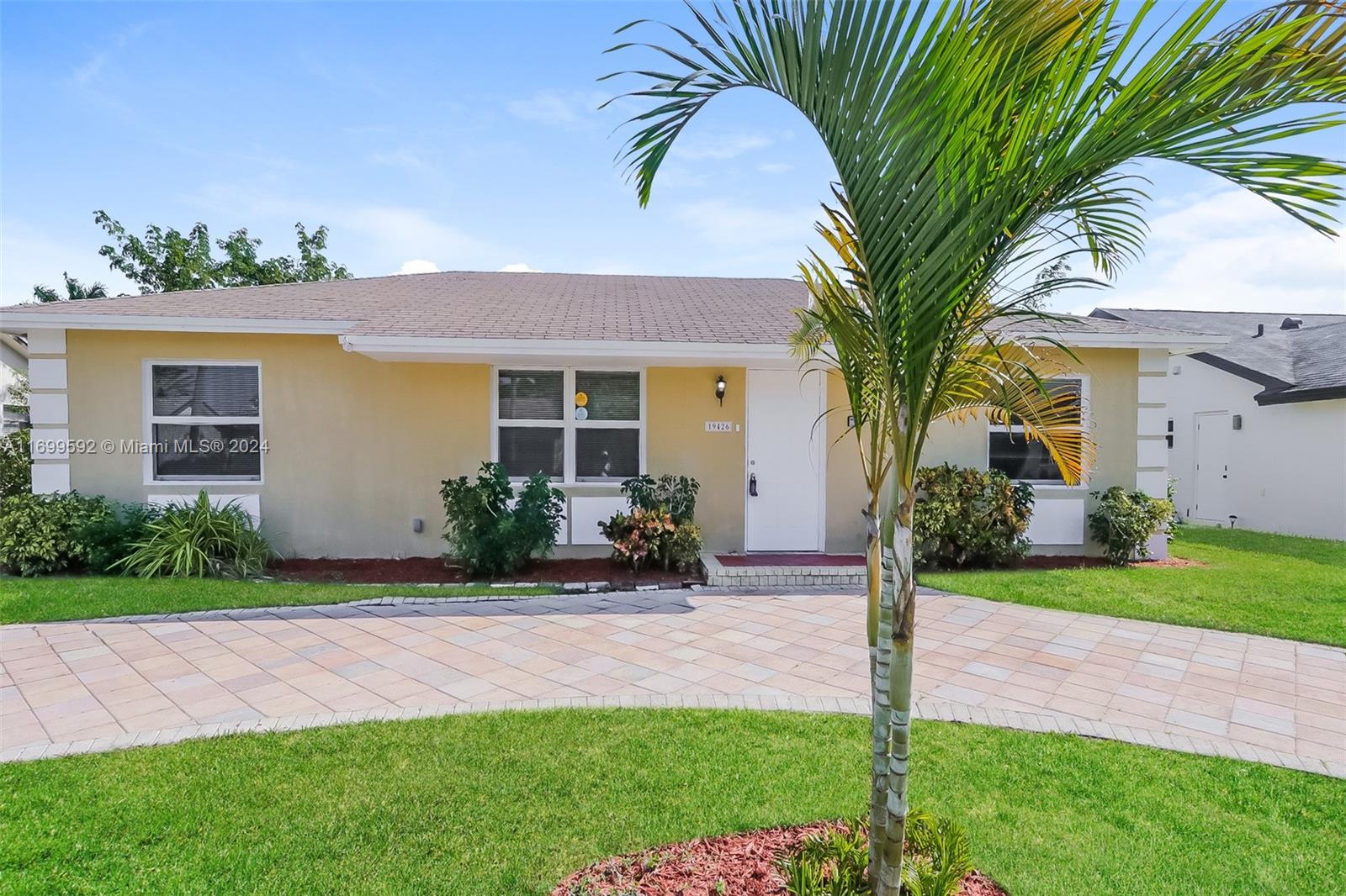 a front view of a house with a garden and palm trees