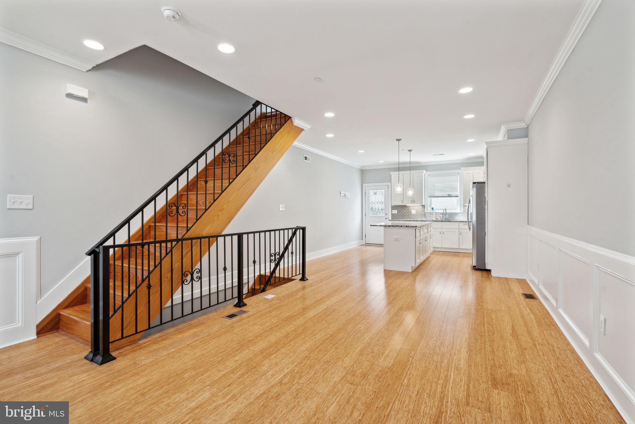 a view of a hallway with wooden floor and kitchen