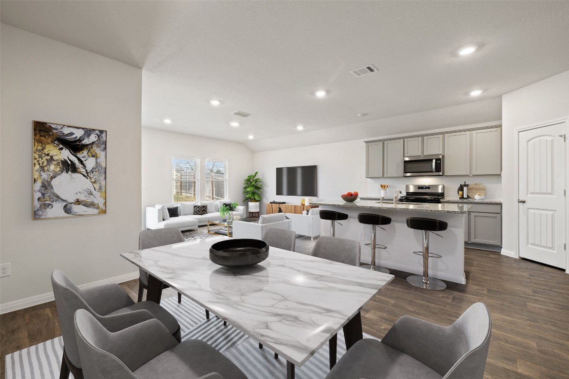 a kitchen with stainless steel appliances granite countertop a table chairs and a refrigerator