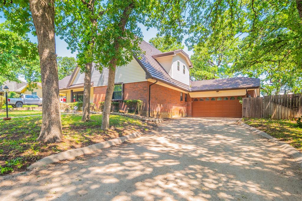 a view of a house with a small yard and large tree