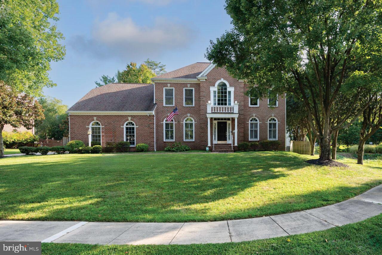 a view of a yard in front of a brick house with large windows