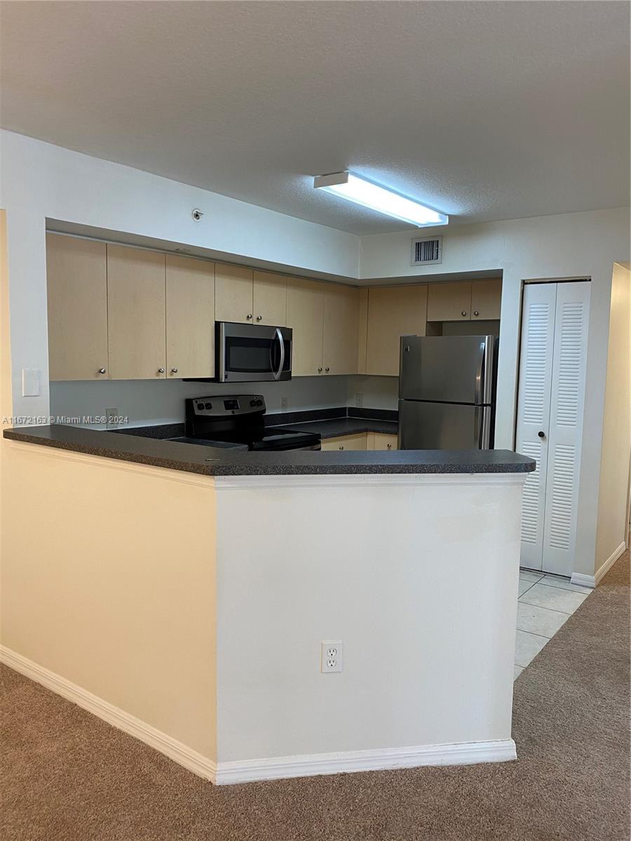 a kitchen with kitchen island a counter top space cabinets and stainless steel appliances