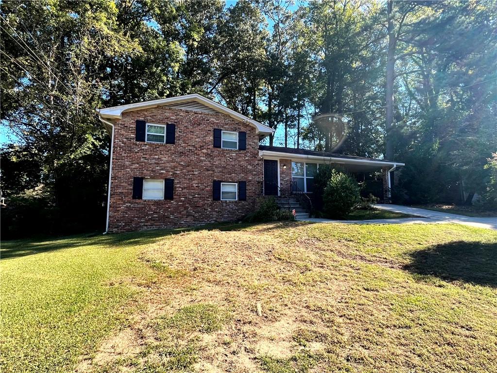 a front view of house with yard and trees in the background