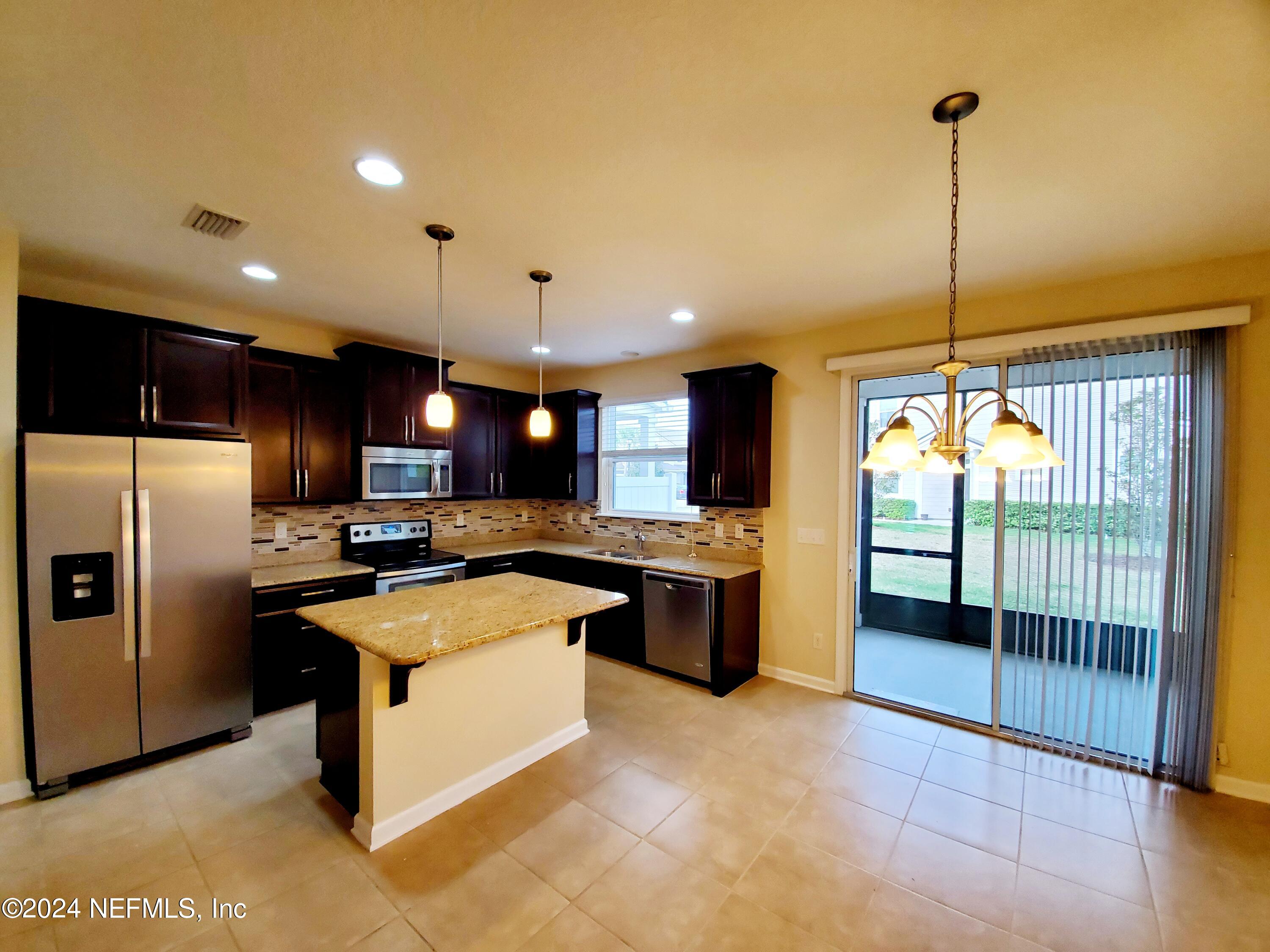 a kitchen with stainless steel appliances granite countertop a stove top oven a sink and a refrigerator