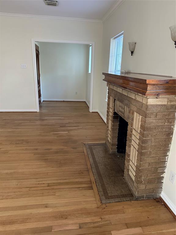 a view of an empty room with wooden floor and a fireplace