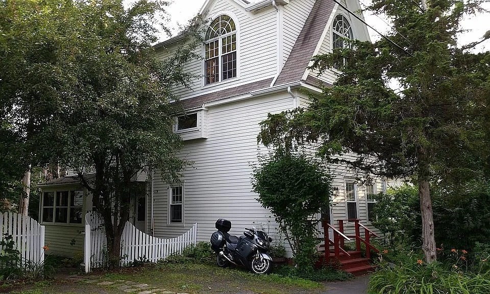 a view of a house with a cars park side of a road