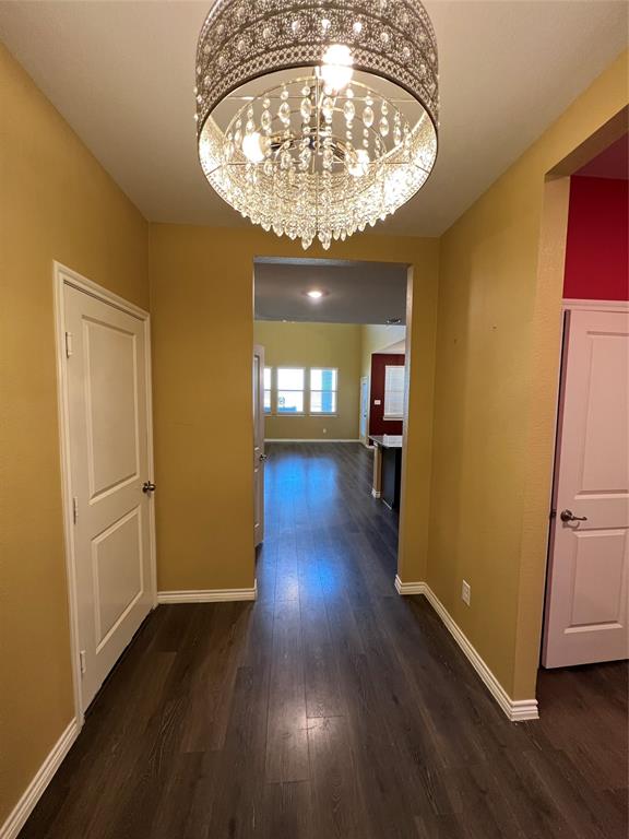 an empty room with wooden floor a chandelier and windows