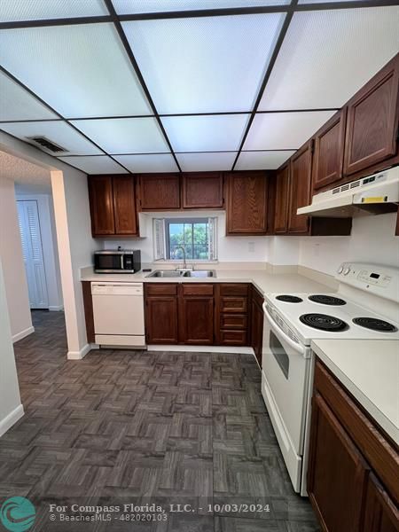 a kitchen with granite countertop a sink cabinets and stainless steel appliances