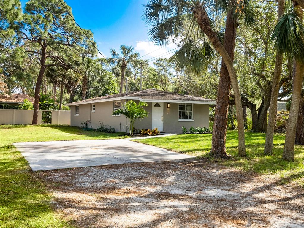 a view of a house with a yard and large trees