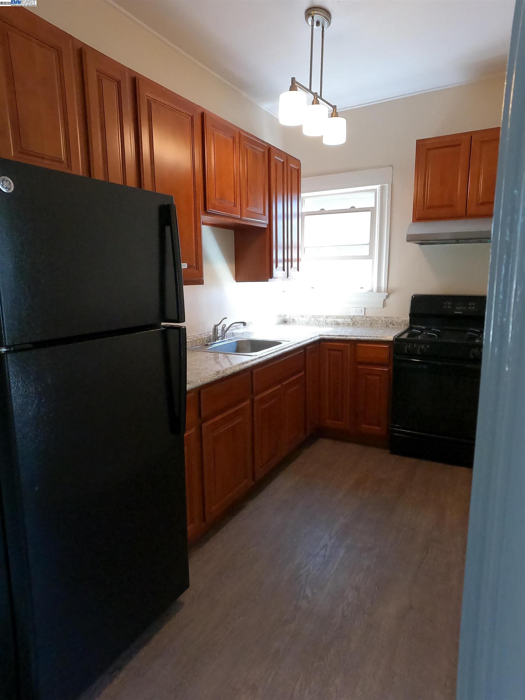 a kitchen with granite countertop a refrigerator and a stove top oven