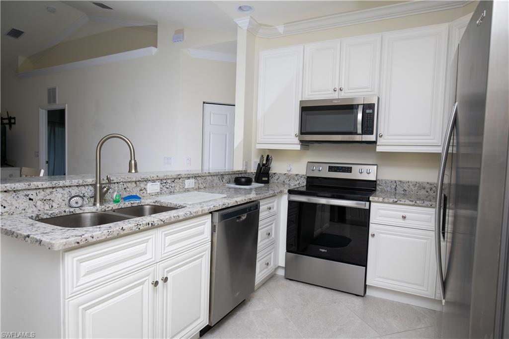 a kitchen with stainless steel appliances granite countertop a sink and white cabinets