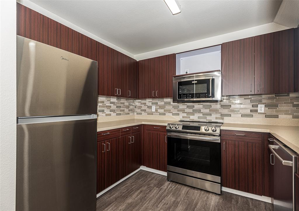 a kitchen with granite countertop a refrigerator stove and microwave