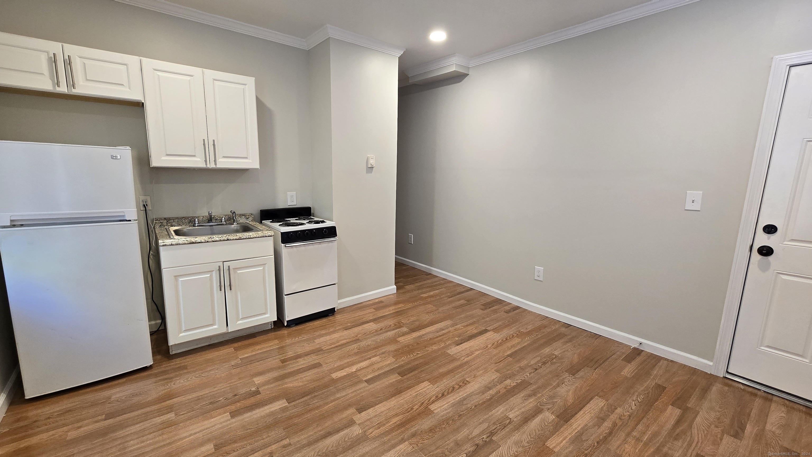 a kitchen with a sink a refrigerator and white cabinets