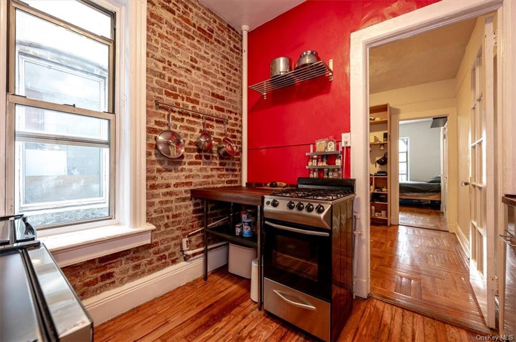 Kitchen with stainless steel range with gas stovetop, a wealth of natural light, brick wall, and dark hardwood / wood-style flooring