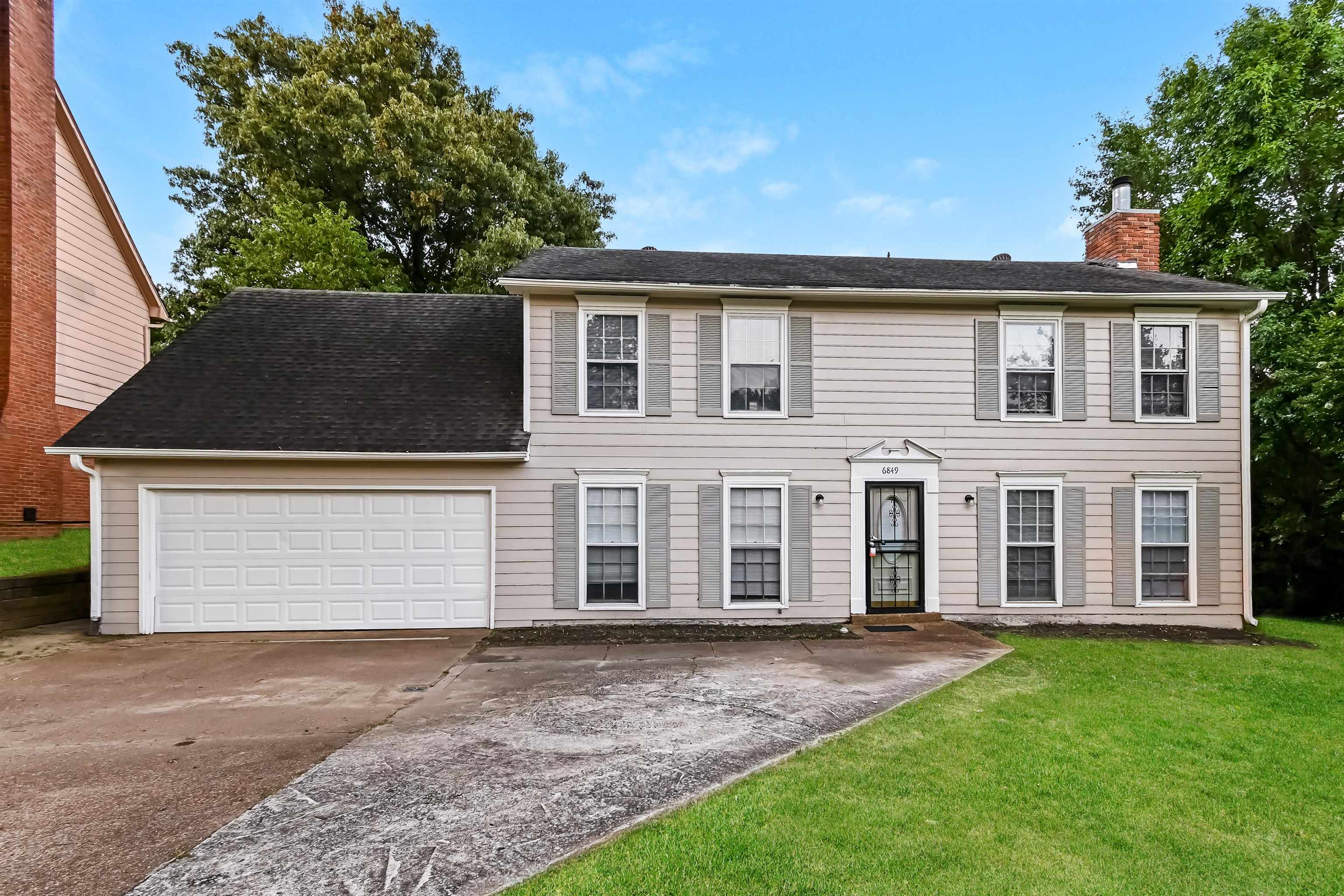 Colonial inspired home with a garage and a front lawn