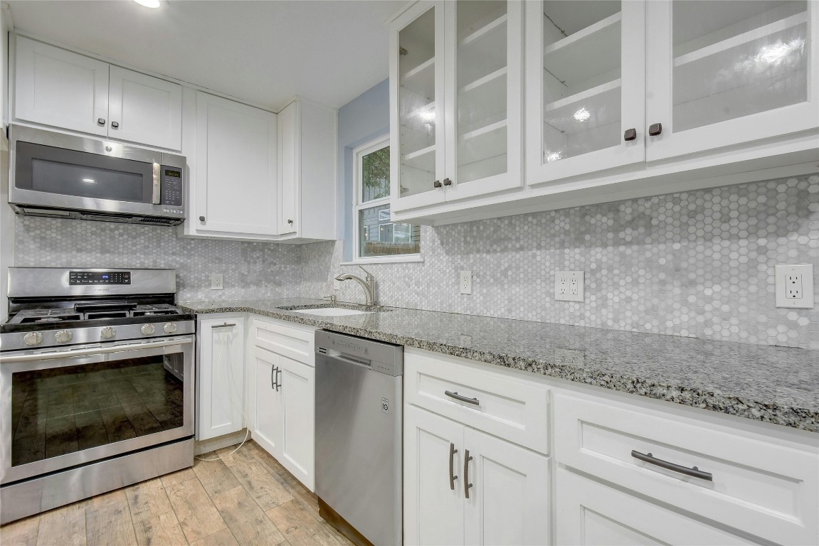 a kitchen with stainless steel appliances granite countertop white cabinets and a stove top oven