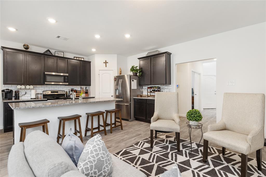 a living room with stainless steel appliances furniture a flat screen tv and kitchen view