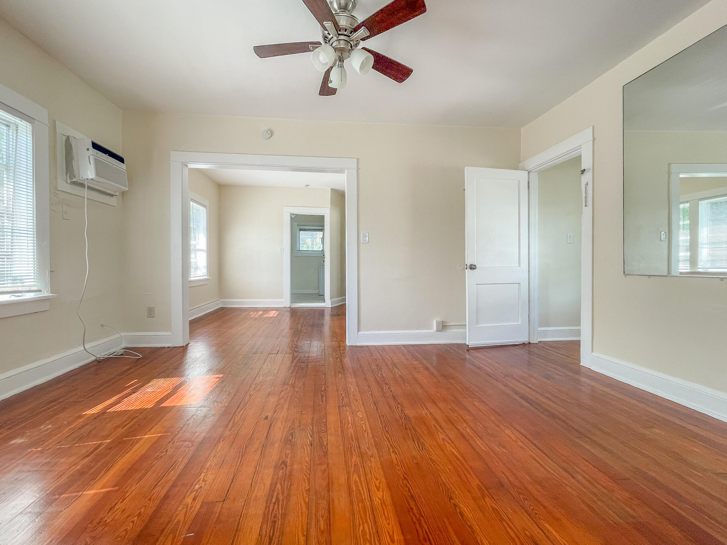 a view of an empty room with wooden floor and a window