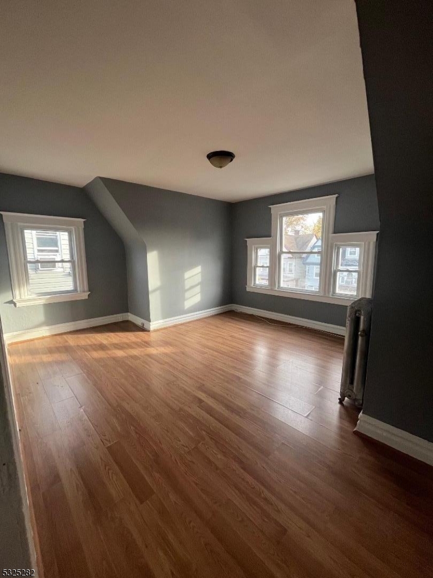 a view of empty room with window and wooden floor