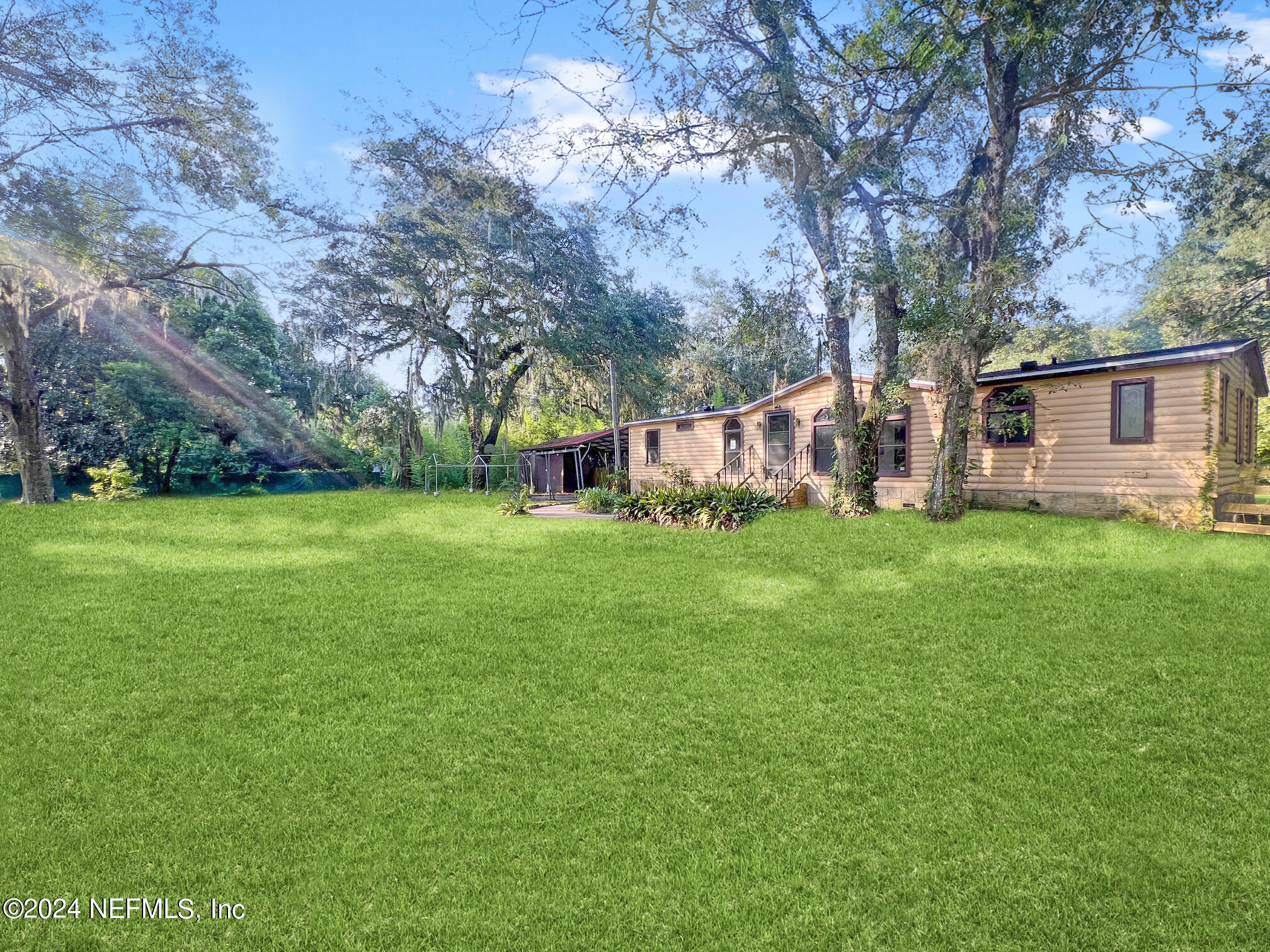 a view of a house with a big yard and large trees