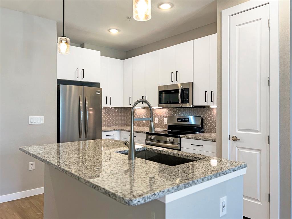 a kitchen with stainless steel appliances granite countertop a sink refrigerator and microwave