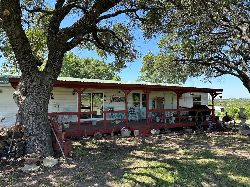 a view of a house with a yard chairs and a large tree