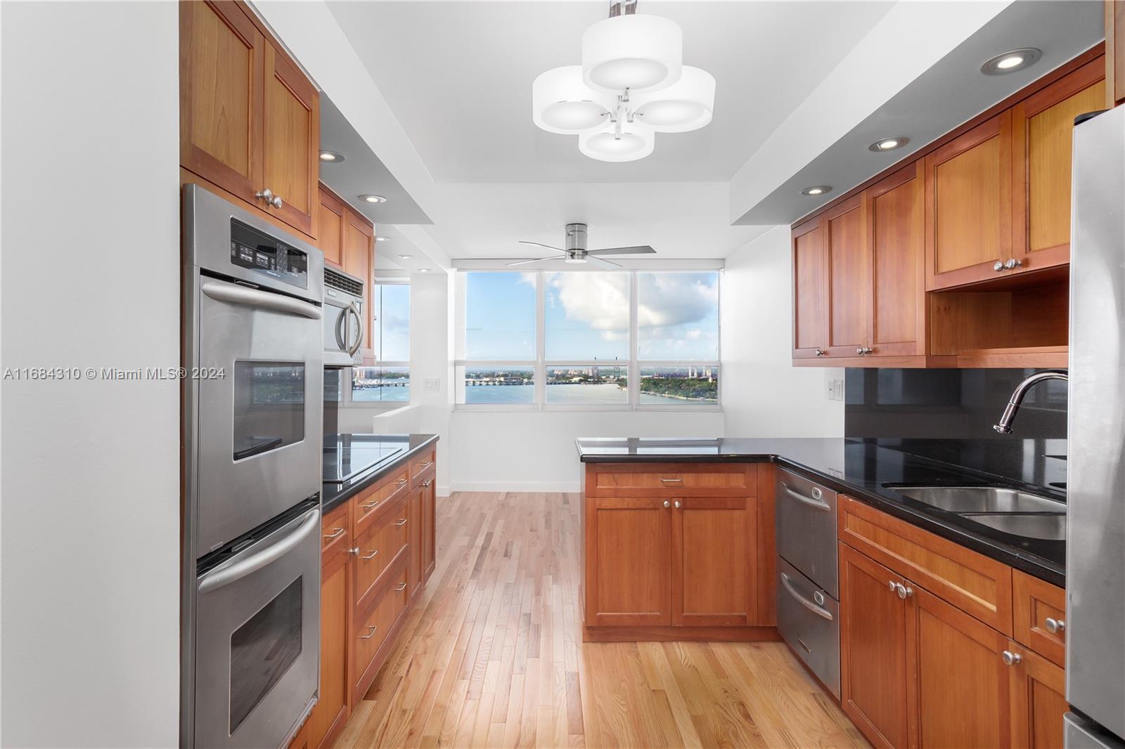 a kitchen with stainless steel appliances granite countertop a sink cabinets and wooden floor