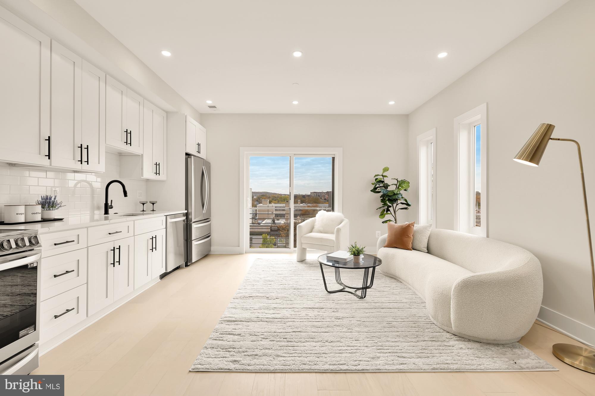 a living room with stainless steel appliances furniture white walls and white cabinets