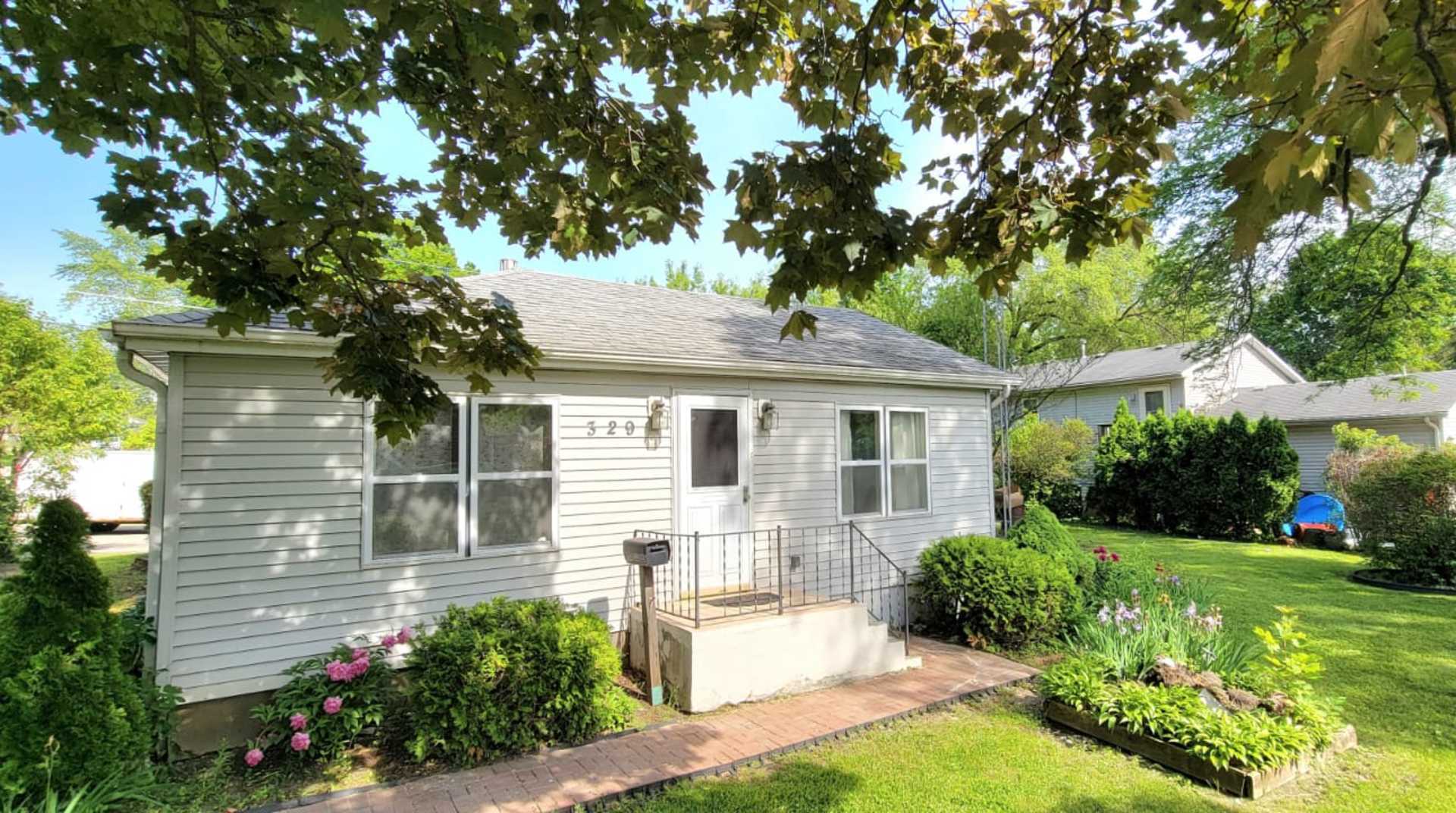 a front view of a house with a yard and potted plants