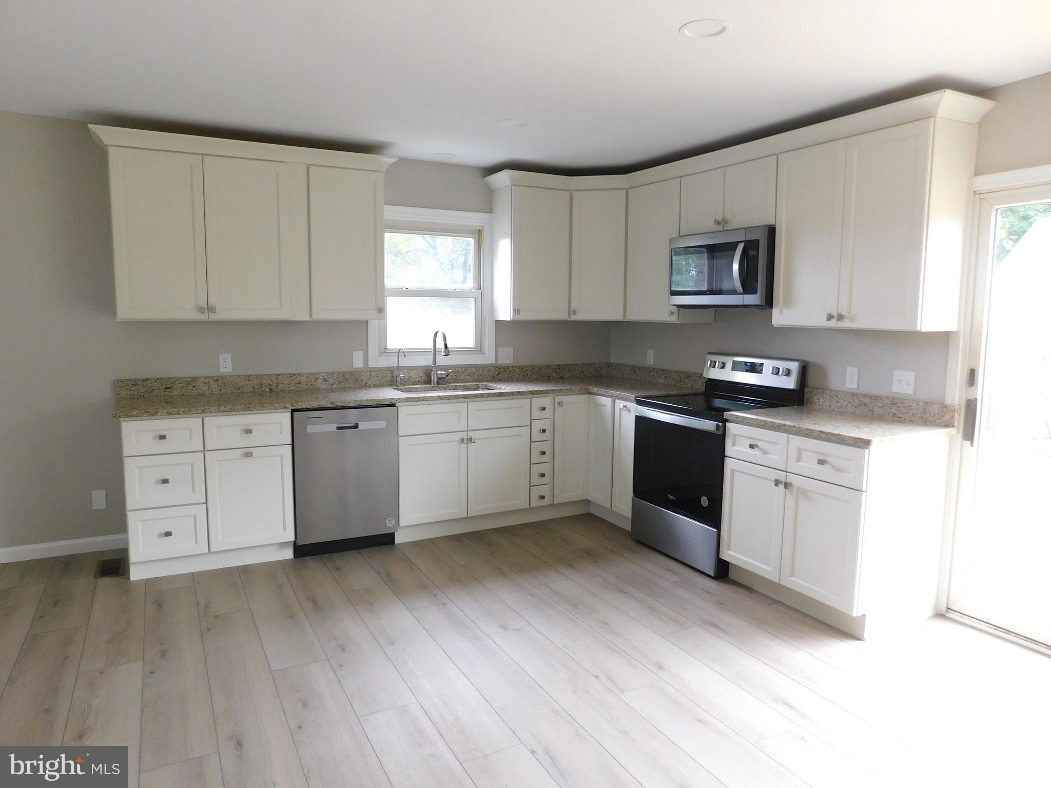 a kitchen with a sink stove cabinets and wooden floor