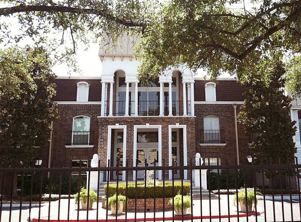 front view of a brick house with large windows and a large tree