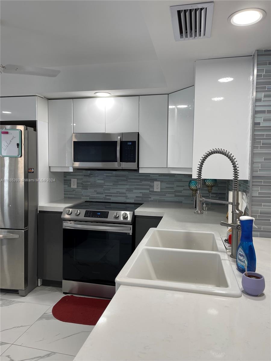 a kitchen with stainless steel appliances granite countertop a stove a sink and a microwave