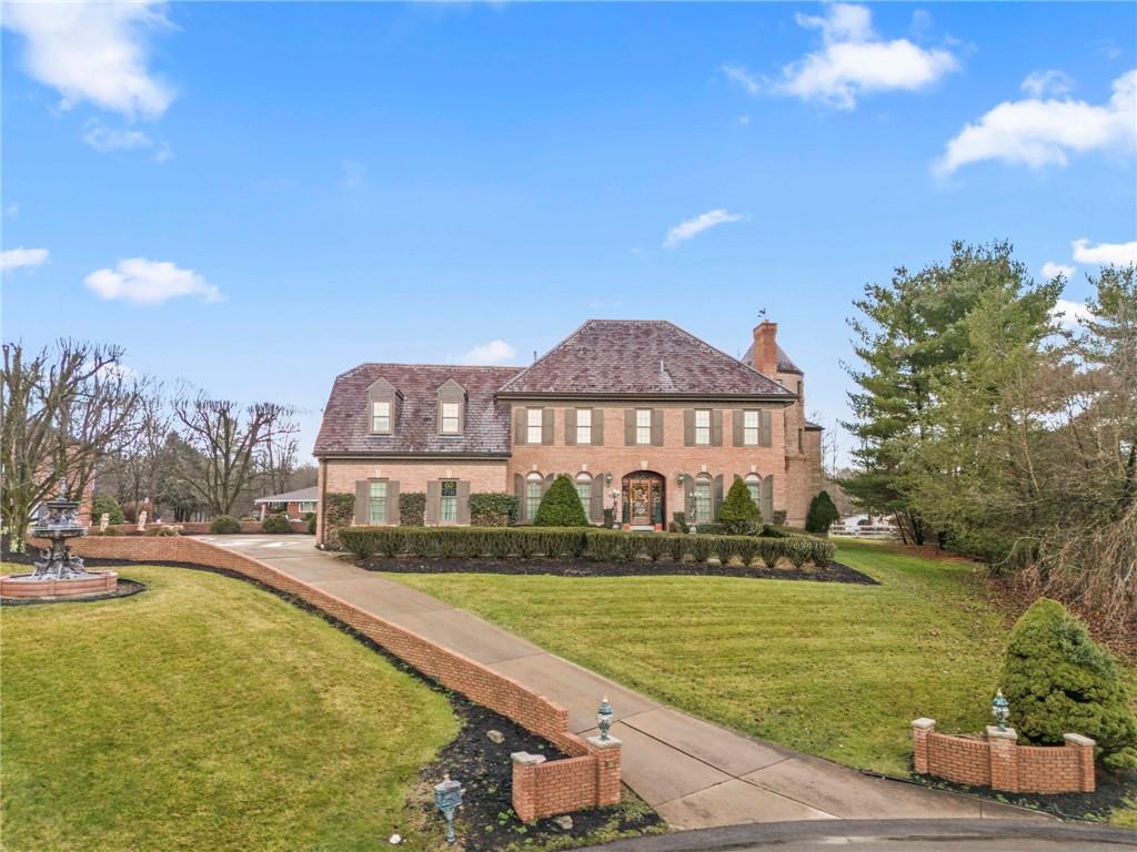 a front view of a house with a garden and lake view