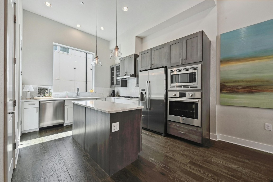 a kitchen with stainless steel appliances kitchen island granite countertop a stove a sink and a refrigerator