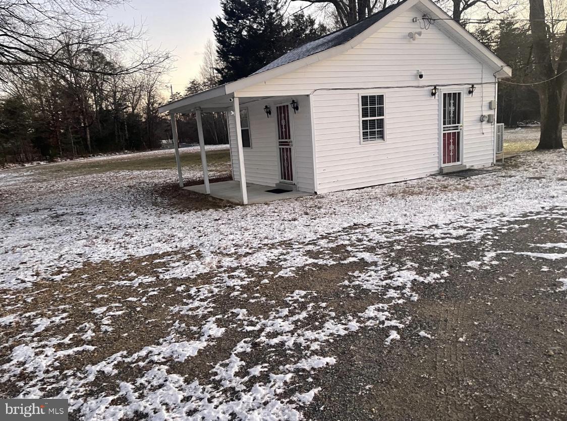 a view of a small white house next to a yard