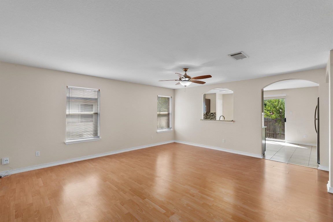 an empty room with wooden floor chandelier fan and windows